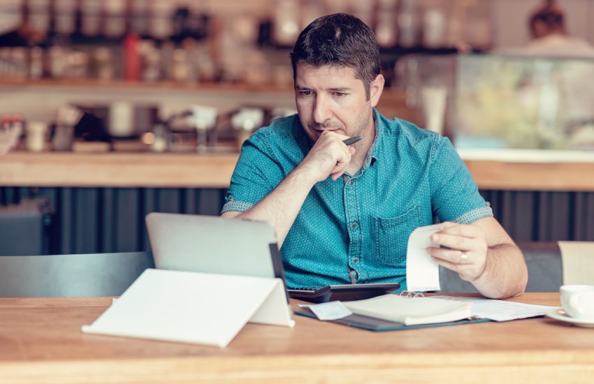 Restaurant owner checking monthly reports on a tablet, bills and expenses of his small business. Start-up entrepreneur concerned about financial reports