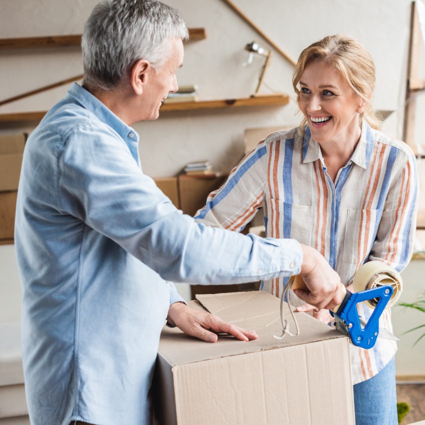 happy elderly couple packing cardboard boxes during relocation