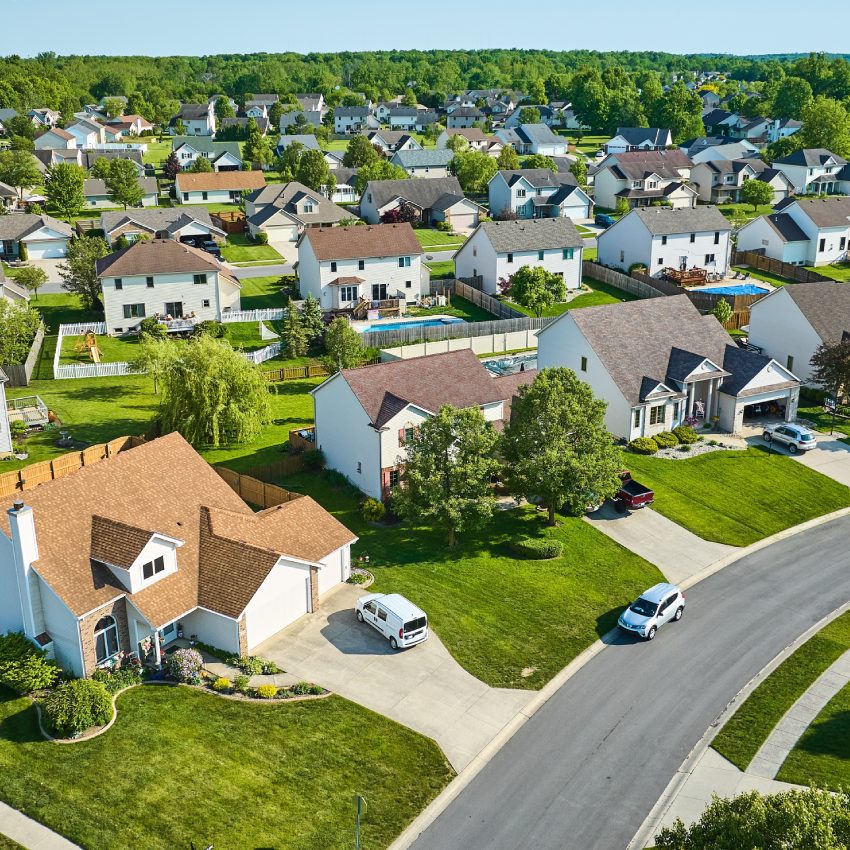 Two story houses in neighborhood aerial with cars in driveways and the street