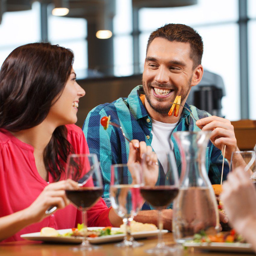 happy couple with friends eating at restaurant
