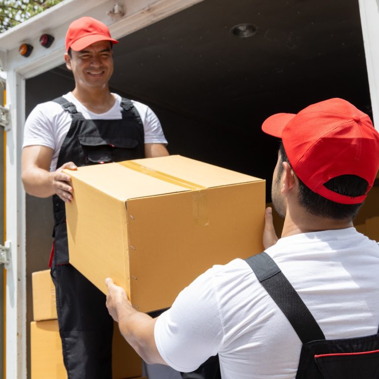 Portrait of two movers unloading boxes and furniture from a pickup truck.