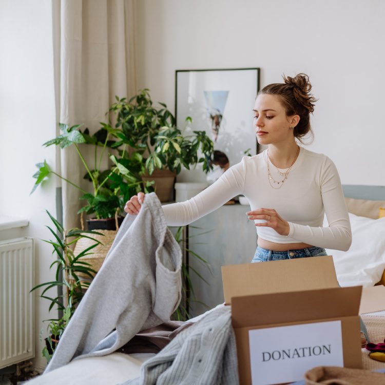 Young woman giving her clothes to charity.