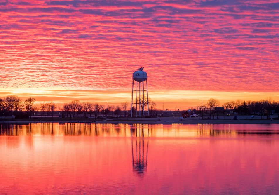BIG LAKE, MN - NOVEMBER 2021 - A Dramatic Sunset Sky over the Big Lake Water Tower Reflects in Big Lake during November Evening
