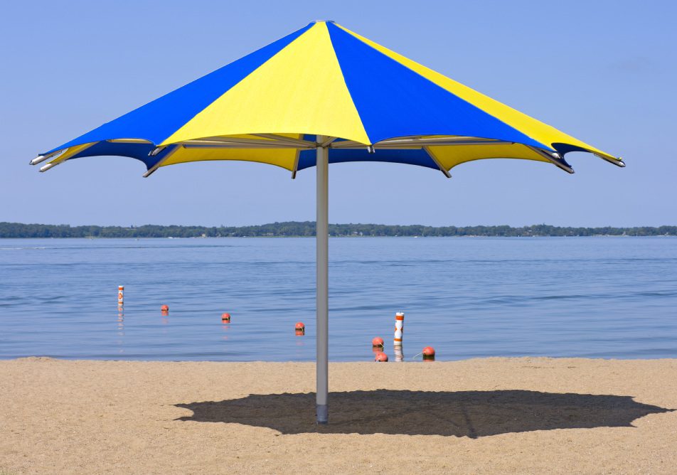 Colorful shade umbrella at sandy beach and shoreline of Lake Waconia Regional Park in Minnesota