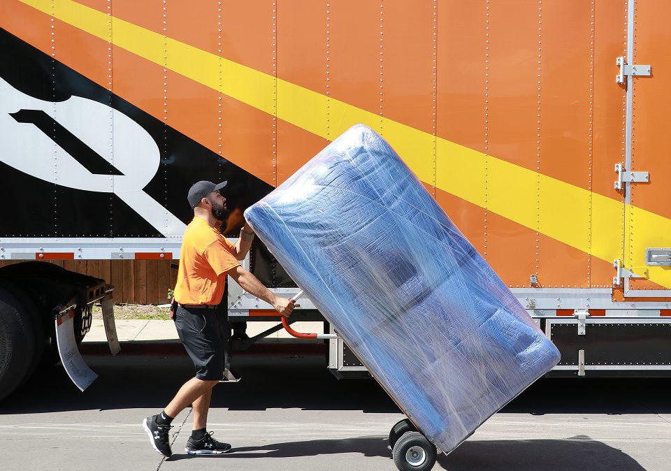 A man is loading a large box onto a truck, illustrating the efforts of international movers.