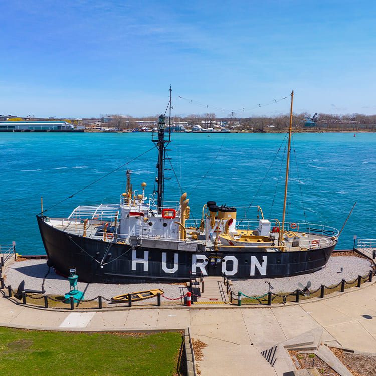 A boat is docked peacefully in the water, surrounded by a serene landscape. Move from Minnesota to Michigan.