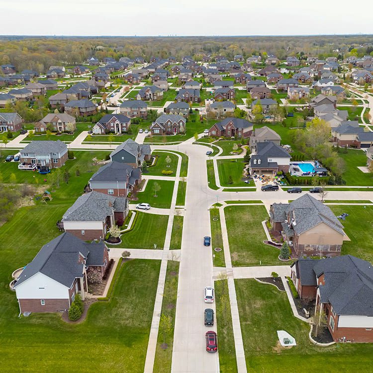 Aerial view of a neighborhood showcasing houses, trees, and streets, illustrating community life in transition.
