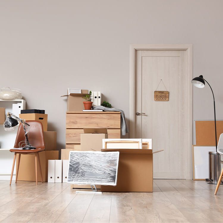A cluttered room filled with boxes and furniture, illustrating a moving home office scenario.