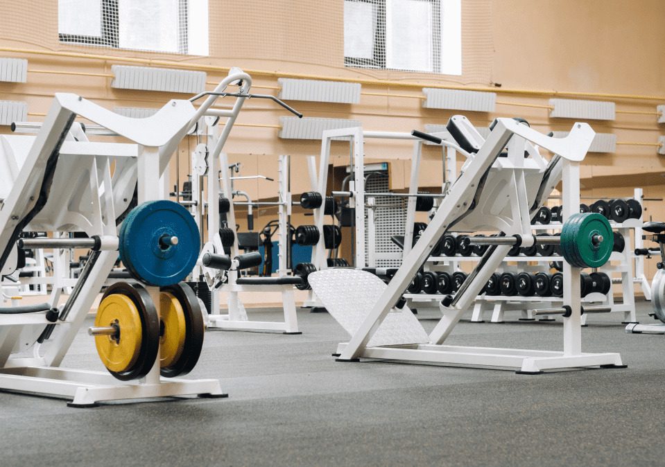 A spacious gym interior featuring various weightlifting machines and free weights arranged neatly on racks.
