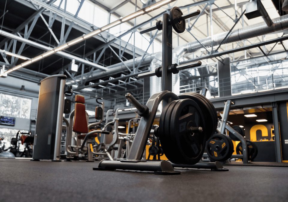 A weightlifting machine with plates in a modern gym, featuring various exercise equipment in the background.