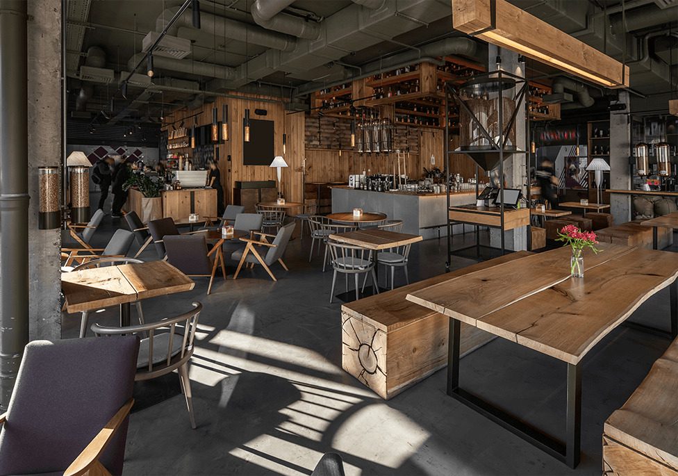 Modern café interior featuring wooden furniture, soft lighting, and a cozy atmosphere with patrons enjoying their time.