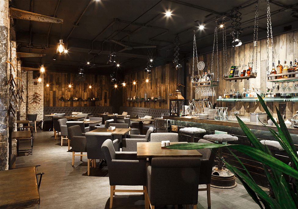 Stylish restaurant interior featuring wooden walls, cozy seating, and a well-stocked bar with ambient lighting.