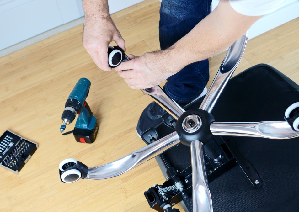 Master repairs office chair with a screwdriver.