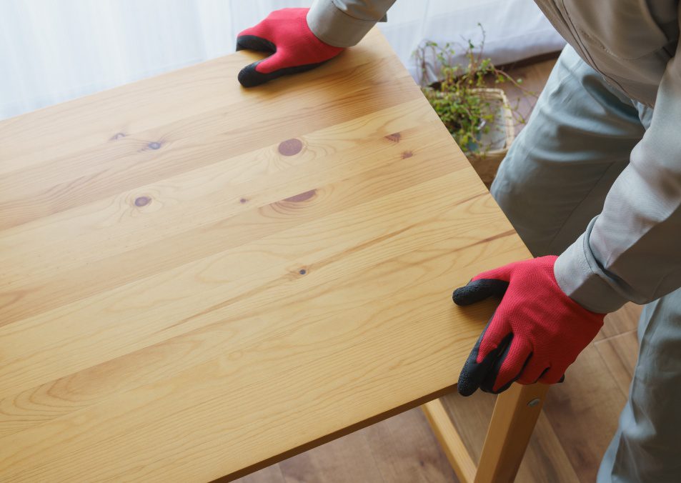 A worker assembling a table. A worker collects unnecessary items.