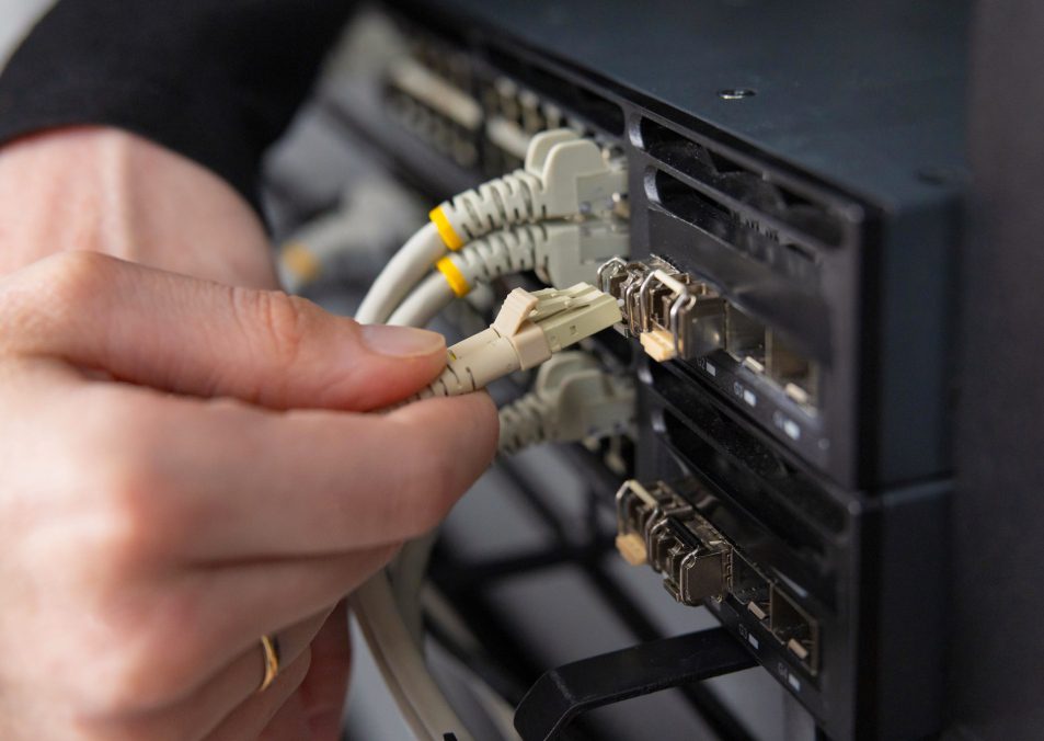 Adult woman technician connects network cables to server hardware in a data center for maintenance and security checks