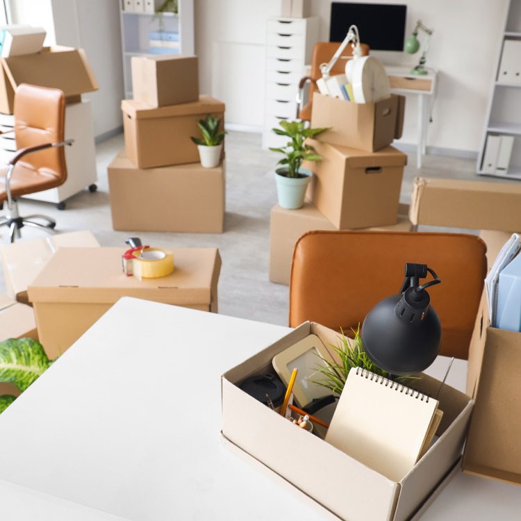 Desk with cardboard boxes in office on moving day